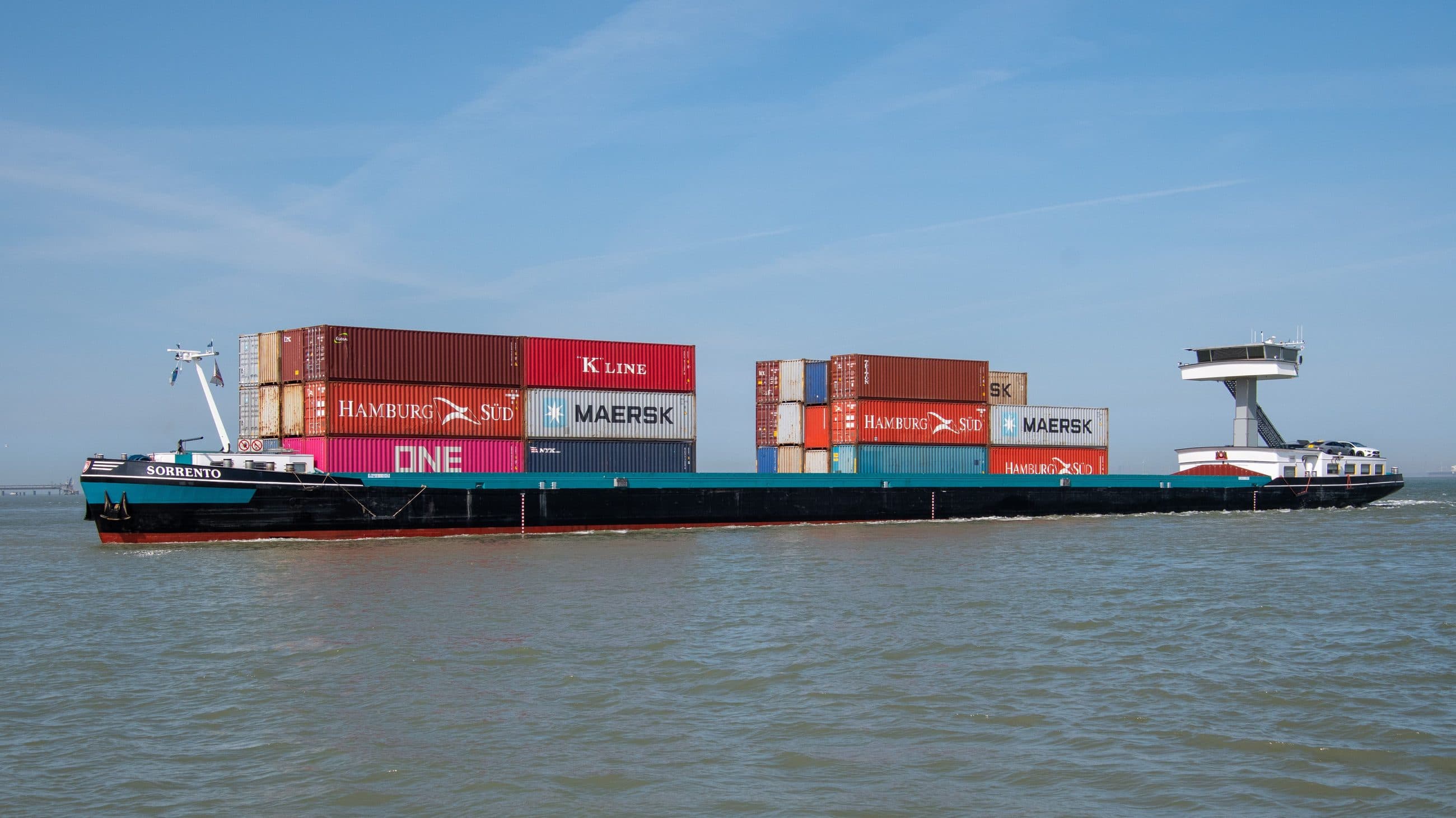 River barge under way loaded with shipping containers stacked two-high