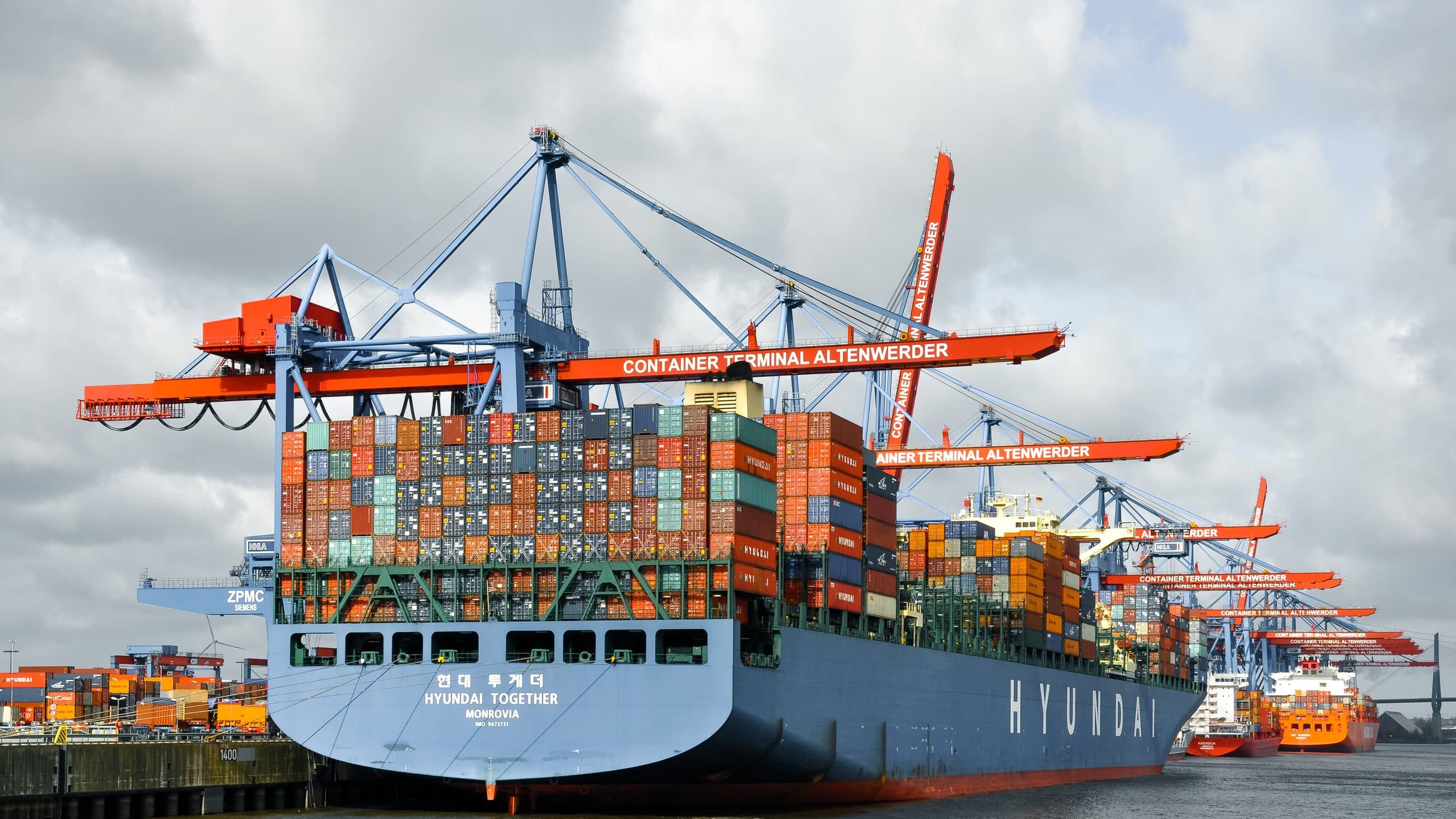 Container ship at berth under gantry cranes, containers stacked on deck