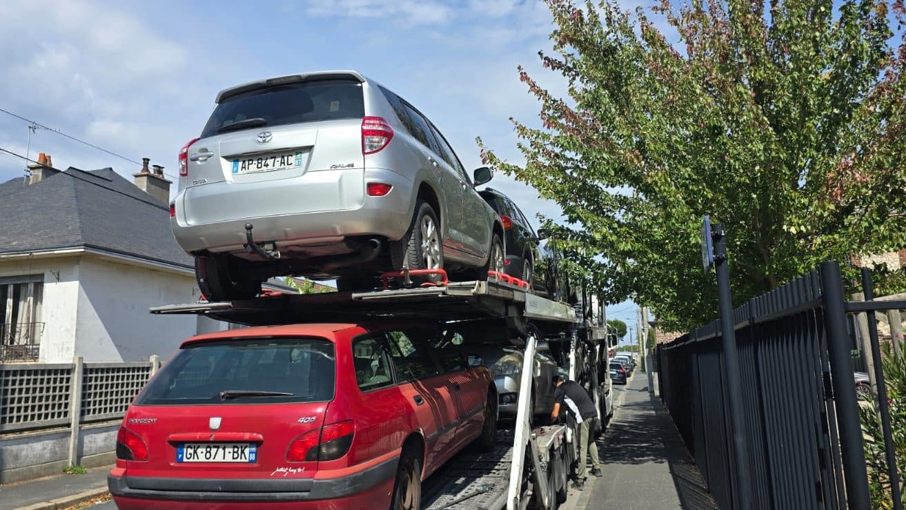 Car carrier parked on a residential street, vehicles lashed on two levels